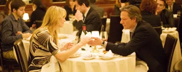 Twom mensen zaten aan de overkant van een eettafel en hielden elkaars hand vast