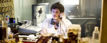 David op een mobiele telefoon met een hoofdtelefoon rond zijn nek
