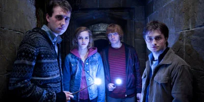 Neville, Hermione, Ron And Harry Stood In A Corridor With Lit Wands